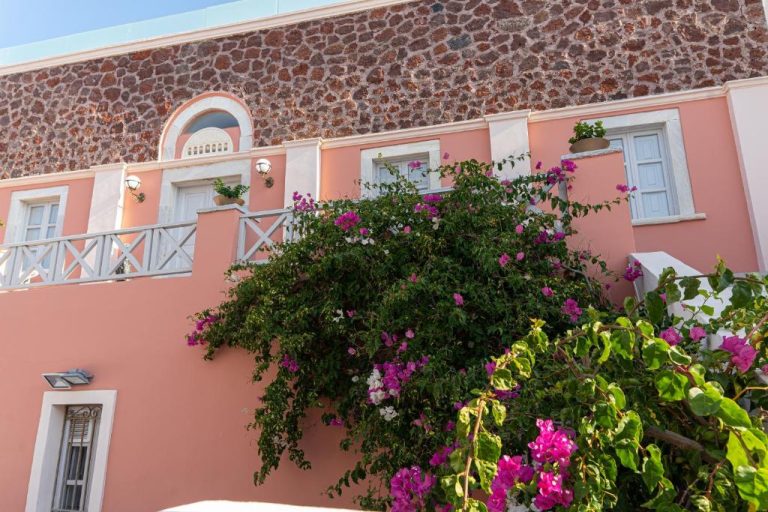 Fachada rosa del The Museum Project Oia en Santorini con buganvillas en flor y arquitectura tradicional griega