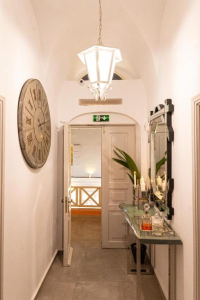 Pasillo elegante con reloj vintage y espejo decorativo en The Museum Project Oia, Santorini