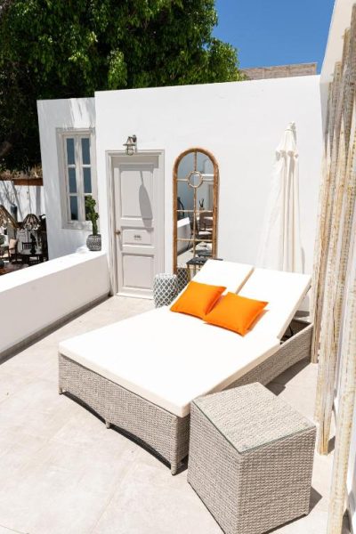 Terraza privada con tumbonas de ratán y cojines naranja en The Museum Project Oia, Santorini