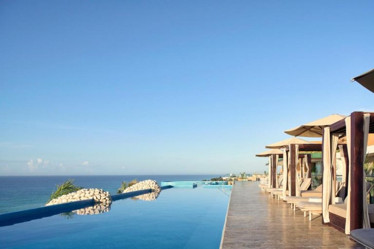 Piscina infinita con camastros y cabañas privadas frente al mar en Hotel Xcaret Arte Adults Only