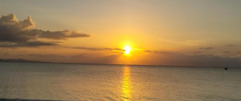 Espectacular atardecer sobre el mar visto desde la playa del Airport Beach Hotel con cielo dorado