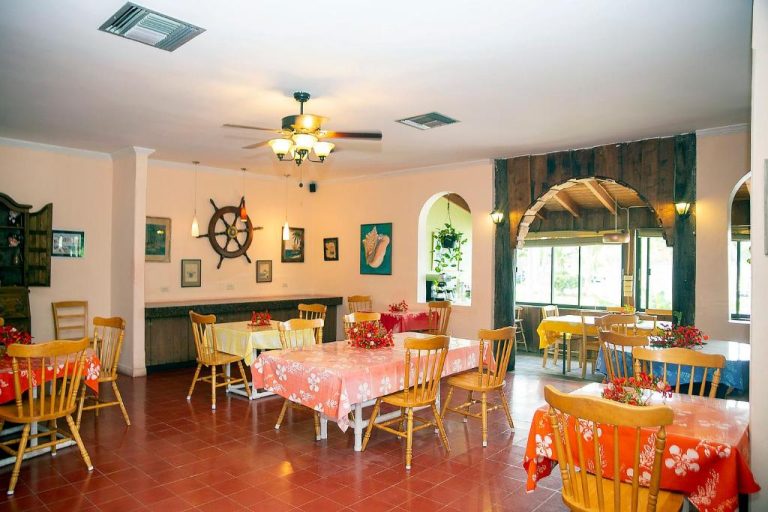 Restaurante interior del Orange Hill Beach Inn con mesas decoradas y ambiente náutico tropical