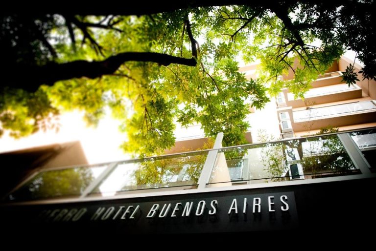 Fachada exterior del Fierro Hotel Buenos Aires rodeada de árboles frondosos y terraza acristalada