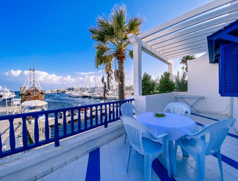 Terraza con mesa y sillas blancas con vistas al puerto deportivo en Marina Cap Monastir Appart'Hôtel
