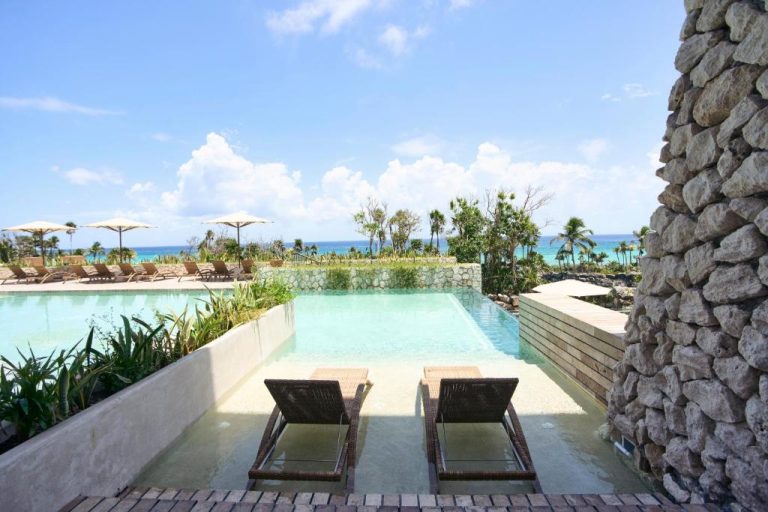 Piscina infinita con tumbonas y vista al mar turquesa en Hotel Xcaret Arte Adults Only México