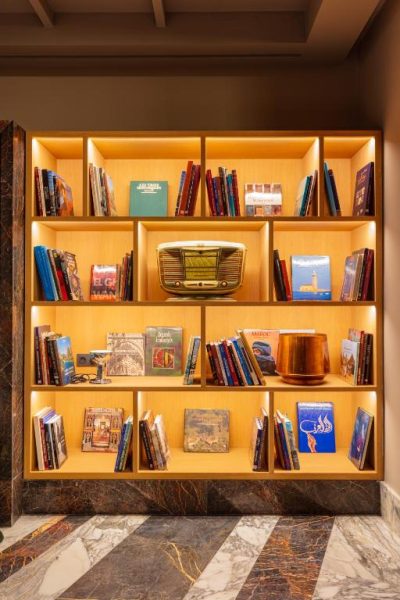 Biblioteca con libros y radio vintage iluminada del Hotel Jadali & Spa con suelo de mármol