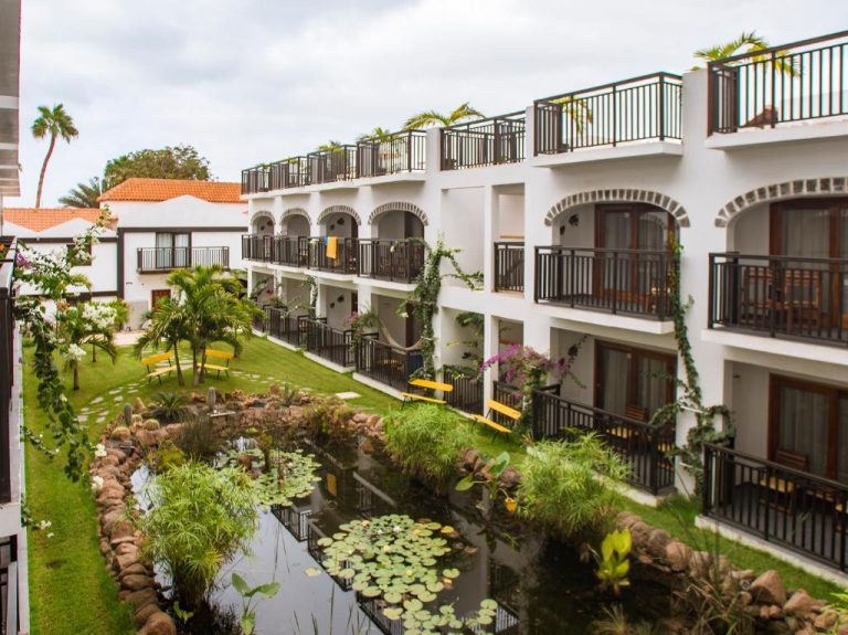 Jardín interior con estanque de nenúfares y balcones del Hotel Odjo d'água en Sal, Cabo Verde