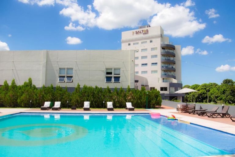 Piscina exterior con tumbonas y vistas al edificio principal del 7 Saltos Resort en Paraguay
