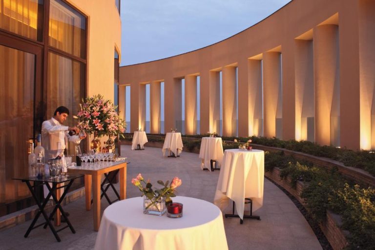 Terraza exterior para eventos con mesas blancas y barra de bar en el Trident Bandra Kurla Mumbai