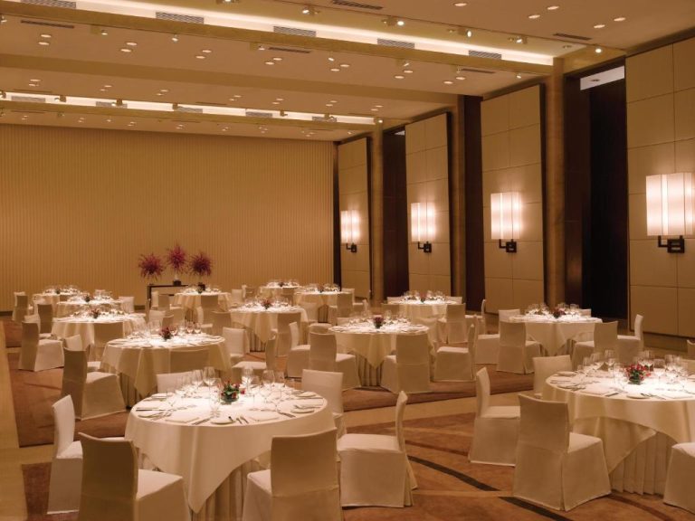 Elegante salón de banquetes con mesas redondas y cristalería fina en el Trident Bandra Kurla