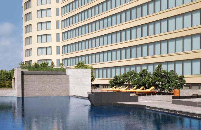 Piscina infinita exterior con tumbonas amarillas y jardín tropical del Trident Bandra Kurla