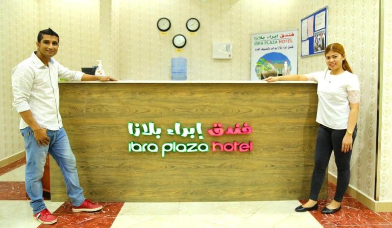 Recepción del Ibra Plaza Hotel con dos empleados sonrientes en el mostrador de bienvenida