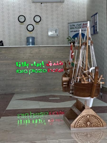 Recepción del Ibra Plaza Hotel con maqueta de barco dhow árabe y relojes mundiales en la pared
