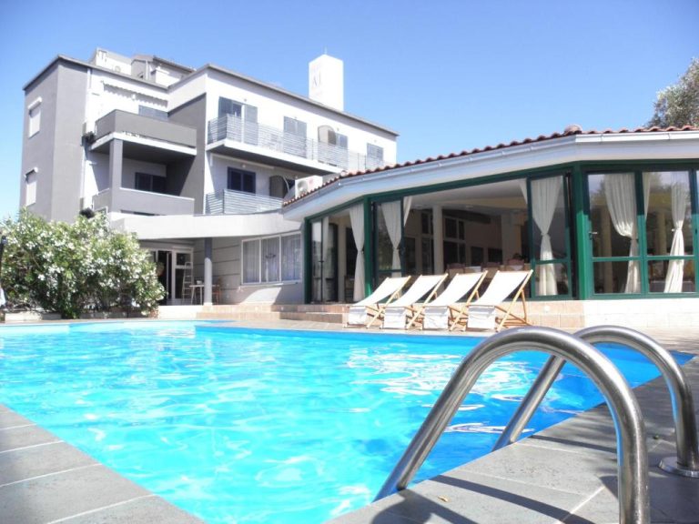 Piscina exterior azul con tumbonas y edificio principal del Levant Residence
