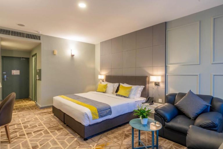 Habitación deluxe con cama doble y sofá de cuero en Manhattan Business Hotel de Male, Maldivas