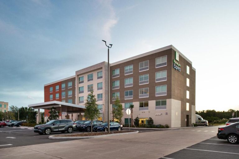 Fachada exterior y aparcamiento del Holiday Inn Express Orlando South Park, hotel moderno de 4 plantas