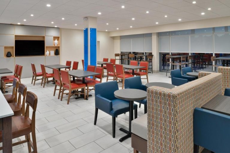 Salón de desayuno con mesas y sillas del Holiday Inn Express Orlando South Park by IHG