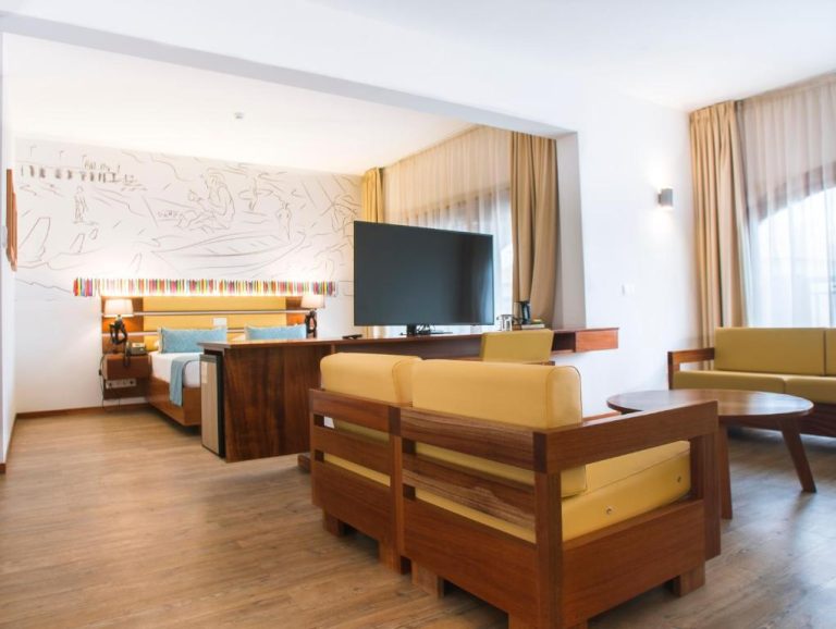 Suite amplia con salón, sofás de madera y televisión del Hotel Odjo d'água