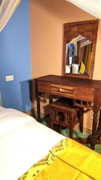 Habitación con tocador de madera tallada y espejo artesanal en Shaba Boutique Hotel