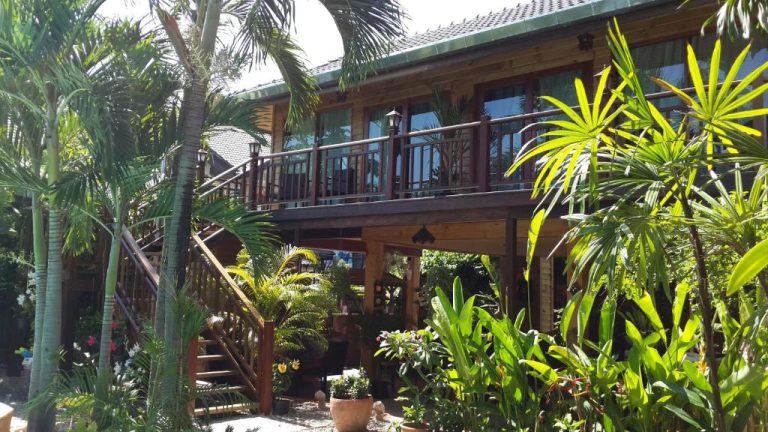 Terraza de madera con jardín tropical y palmeras en Liam's Guesthouse Adults Only