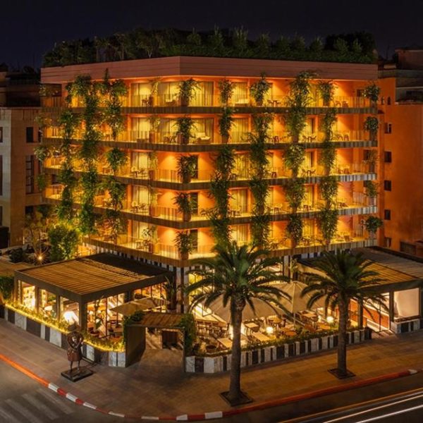 Fachada exterior iluminada del Hotel Jadali & Spa con jardines verticales y terraza restaurante de noche
