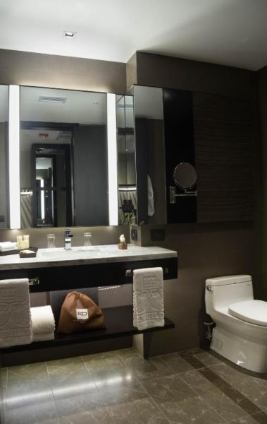 Baño moderno de lujo con tocador de mármol y espejo iluminado en Eb Hotel by Eurobuilding Quito Airport