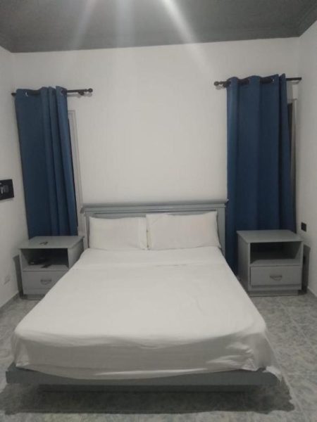Habitación doble con cama matrimonial y cortinas azules en Residencial Mignoli