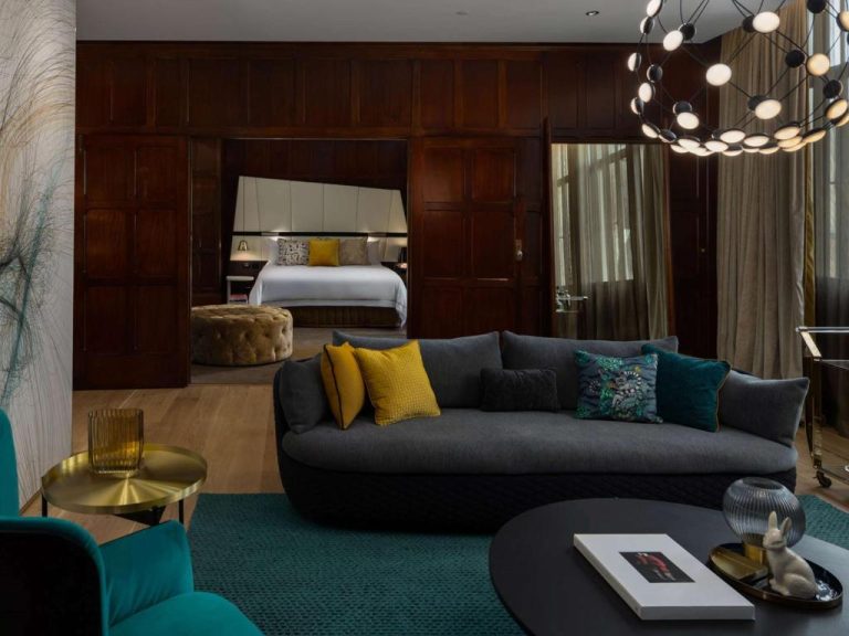 Suite de lujo del QT Sydney con salón moderno, sofá gris y acceso al dormitorio con decoración contemporánea