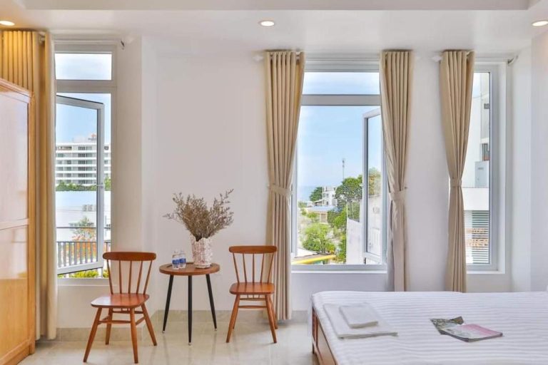 Habitación luminosa con camas y sillas de madera con vistas al mar en Bao Phuc Hotel