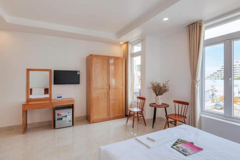 Habitación doble luminosa con escritorio de madera, armario y TV en Bao Phuc Hotel