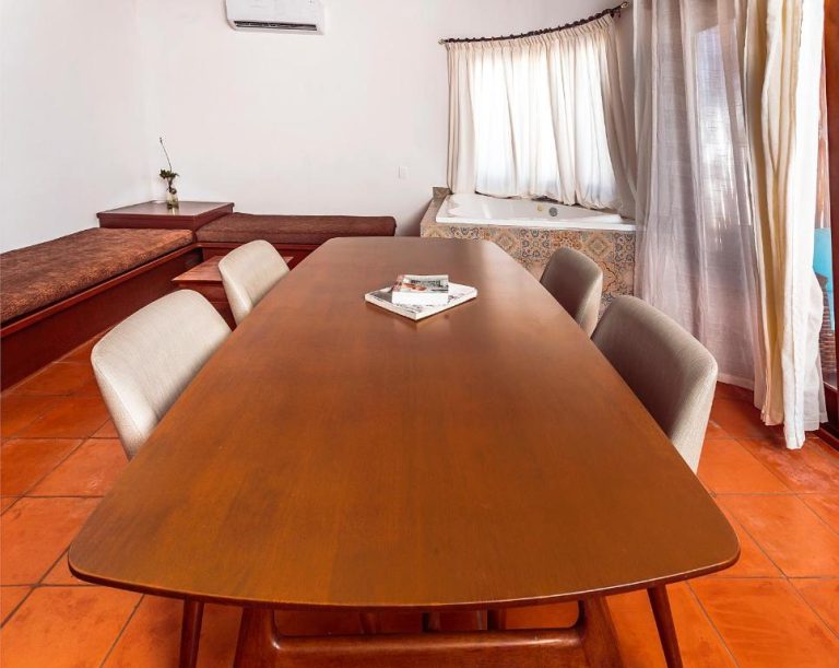 Comedor con mesa de madera y jacuzzi integrado en suite del Fabiola Condo Hotel
