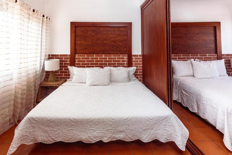 Habitación doble con cama matrimonial y cabecero de madera en Fabiola Condo Hotel