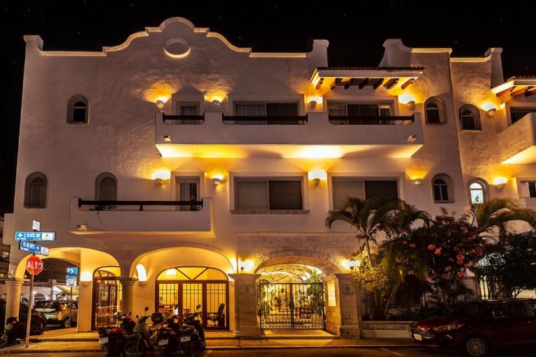Fachada nocturna iluminada del Fabiola Condo Hotel con arquitectura colonial y palmeras