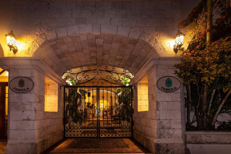 Entrada principal con arco de piedra iluminada de noche del Fabiola Condo Hotel