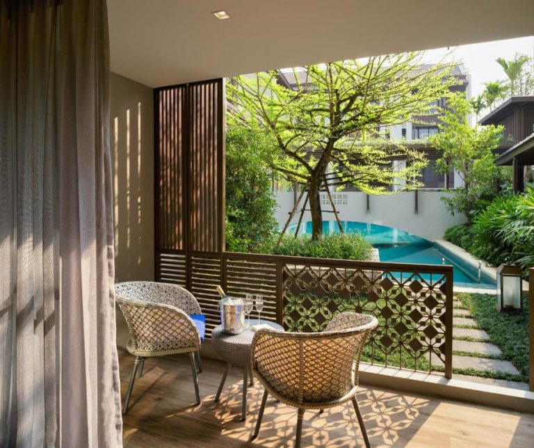 Terraza privada con sillas de ratán y vistas a la piscina del Maladee Rendezvous Hotel Chiang Mai