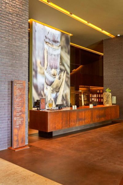 Recepción principal del Saccharum Resort and Spa con mostrador de madera y mural decorativo de caña de azúcar