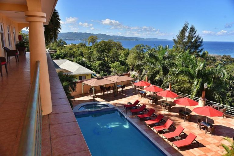 Piscina exterior con tumbonas rojas y terraza con vistas al mar del Hotel Grand A View Jamaica