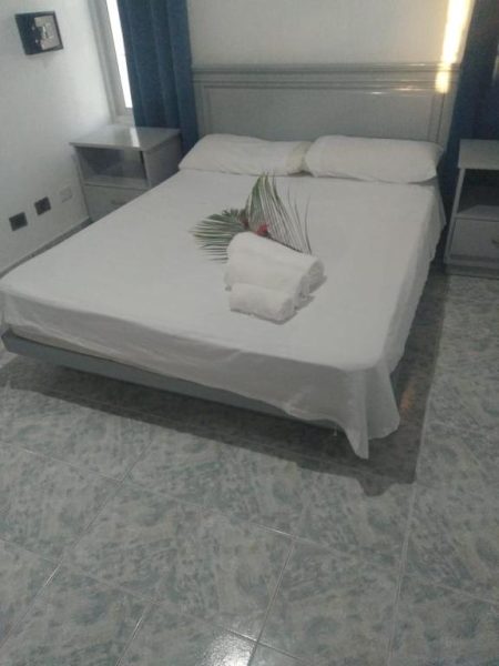 Habitación doble con cama matrimonial blanca y toallas decoradas en Residencial Mignoli