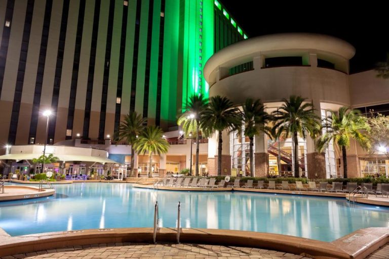 Piscina exterior iluminada de noche en el Rosen Centre Hotel Orlando Convention Center con palmeras
