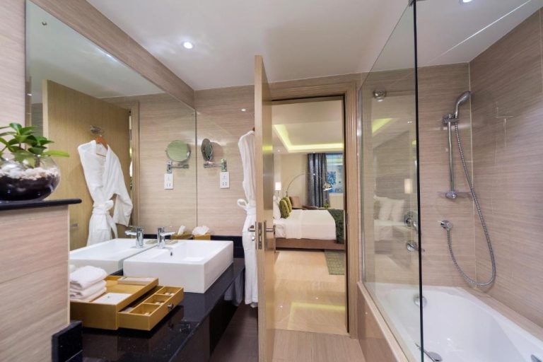 Baño de suite con bañera, ducha de cristal y doble lavabo en Centara Muscat Hotel Oman