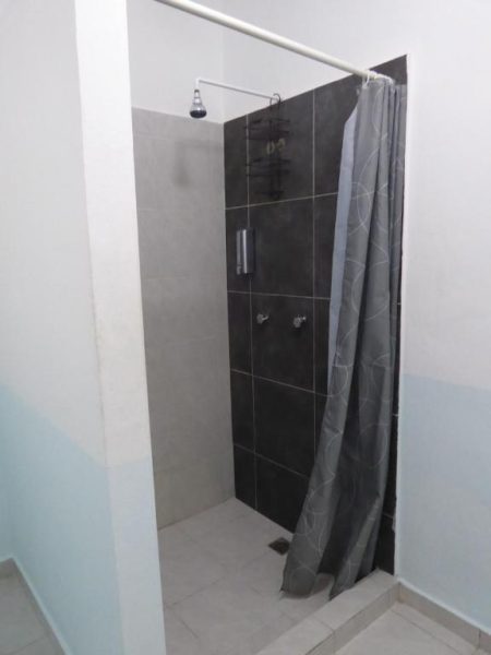 Ducha moderna con azulejos oscuros y cortina gris en el baño del Hotel Claro de Luna