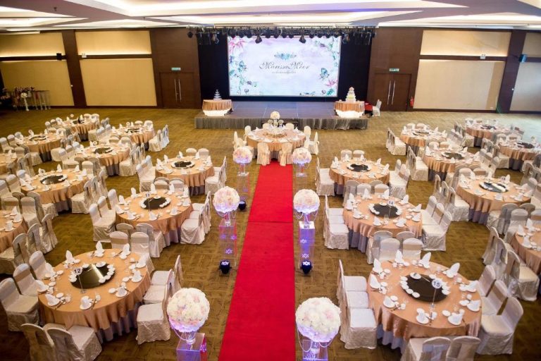 Salón de bodas con alfombra roja y mesas decoradas en el Ixora Hotel Penang