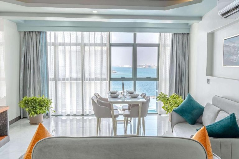 Salón luminoso con comedor y vistas al mar en el hotel Marukab Plaza, decoración moderna en tonos blancos y azules