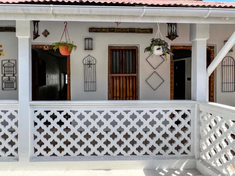 Terraza colonial con balustrada blanca y plantas colgantes del Emerald Palm Courtyard Hotel