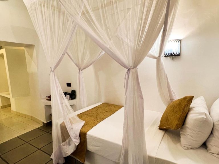 Habitación con cama dosel y mosquitera blanca en Emerald Palm Courtyard Hotel