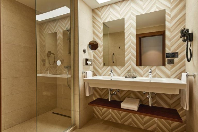 Baño moderno con lavabo doble y ducha acristalada en el Hotel Riu Jambo All Inclusive
