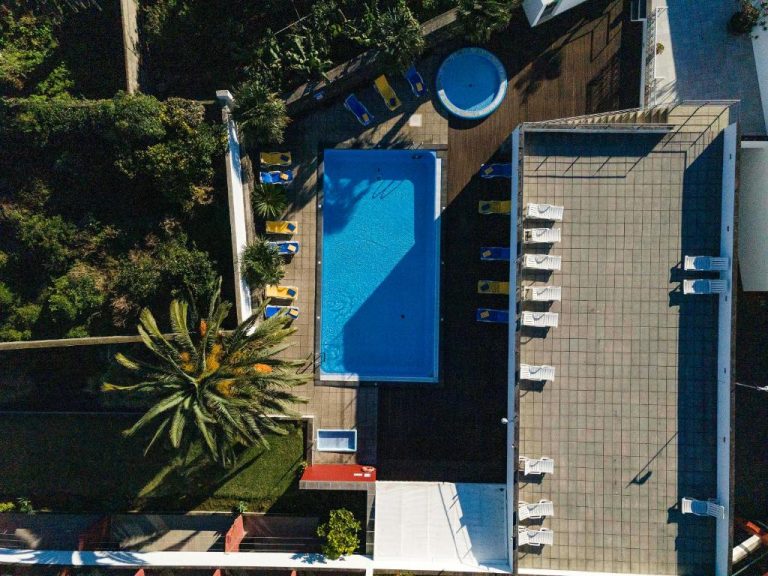 Vista aérea de la piscina exterior con tumbonas del Antillia Hotel rodeada de jardines tropicales