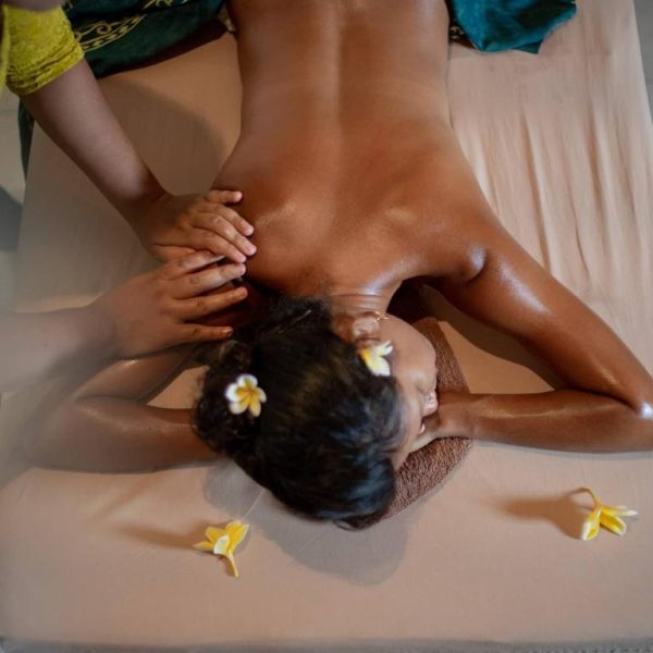 Masaje relajante en el spa del Bruga Boutique Hotel con flores de frangipani decorando la camilla