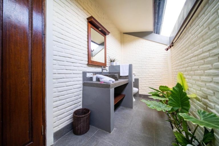 Baño semiabierto con lavabo de cemento y paredes de ladrillo blanco en Bruga Boutique Hotel