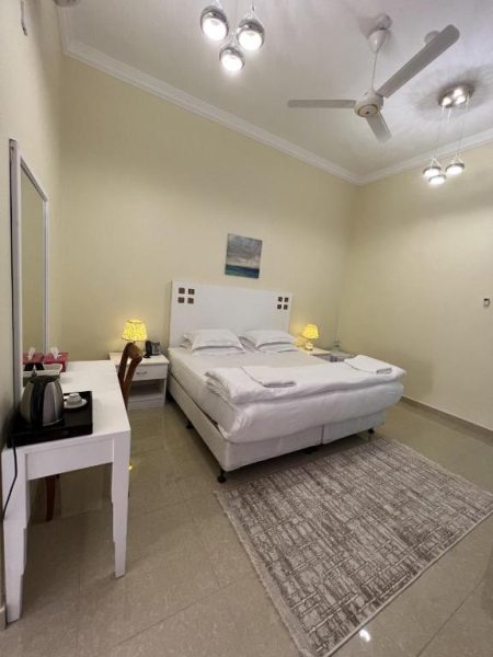 Habitación doble con cama matrimonial blanca y escritorio en Ibra Plaza Hotel